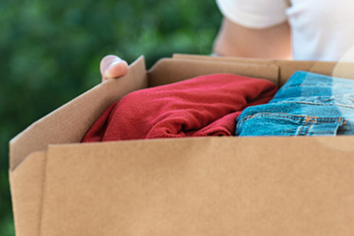 Person holding box of old clothes