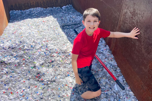 Boy standing in dumpster of pull tab items