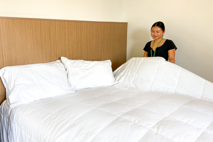 Volunteer making bed in guest room