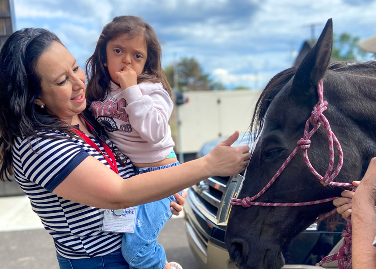 Mom and daughter petting horse