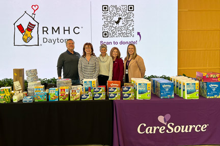 RMHC Dayton staff and CareSource employees standing behind tables with donations of items