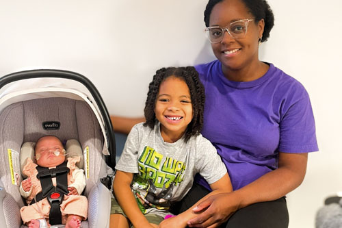 Mom, son, and baby daughter in front of white wall