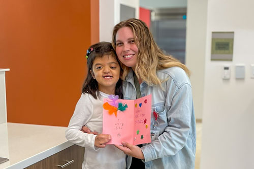 Staff hugging little girl and holding birthday card