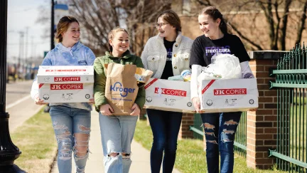 group of teenage girls walking together carrying armloads of donations for RMHC Dayton
