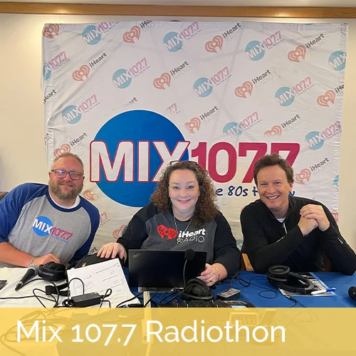 mix 107.7 radio hosts infront of radio logo backdrop; mix 107.7 radiothon text written at bottom