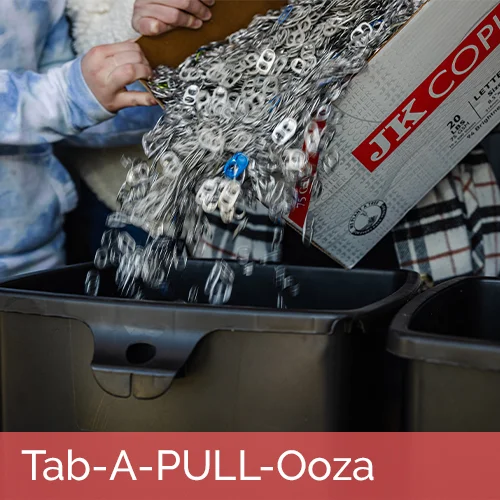 group of volunteers working together to add a box of pull tabs to a collection bin; tab-a-pull-ooza text written at bottom